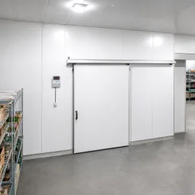Spacious, modern UK cold room interior with clean white PIR insulated panels and a robust sliding door.