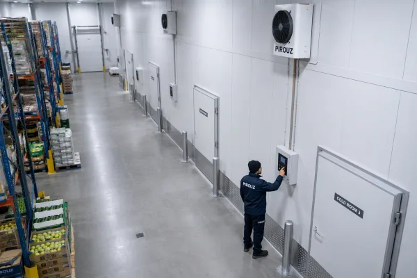 Modern UK commercial cold storage interior with technician inspecting controls.